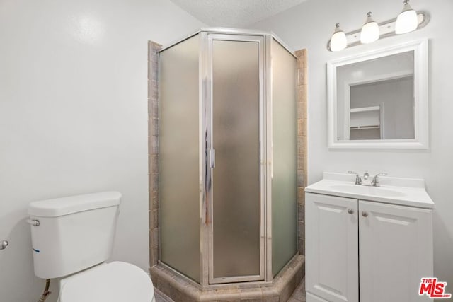 bathroom featuring toilet, a textured ceiling, walk in shower, and vanity