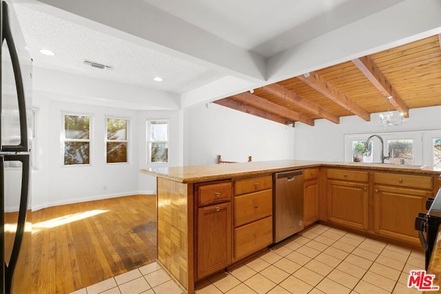 kitchen featuring black refrigerator, sink, kitchen peninsula, stainless steel dishwasher, and beam ceiling