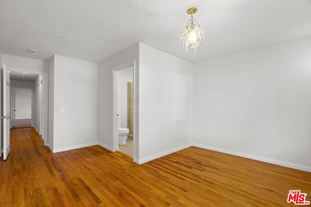 unfurnished room with a textured ceiling and wood-type flooring