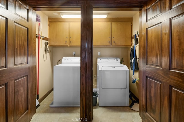 clothes washing area with cabinets and washing machine and dryer