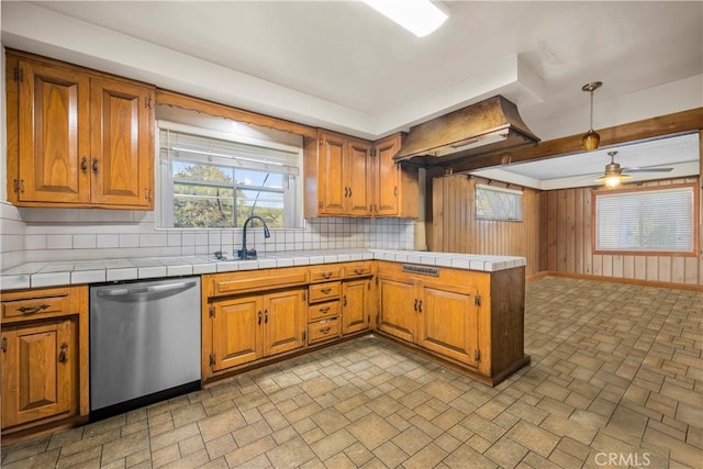 kitchen with tasteful backsplash, stainless steel dishwasher, ceiling fan, pendant lighting, and tile countertops