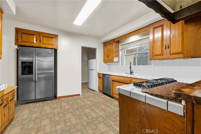 kitchen featuring appliances with stainless steel finishes, backsplash, tile countertops, and sink