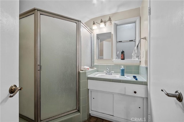 bathroom featuring decorative backsplash, walk in shower, and vanity