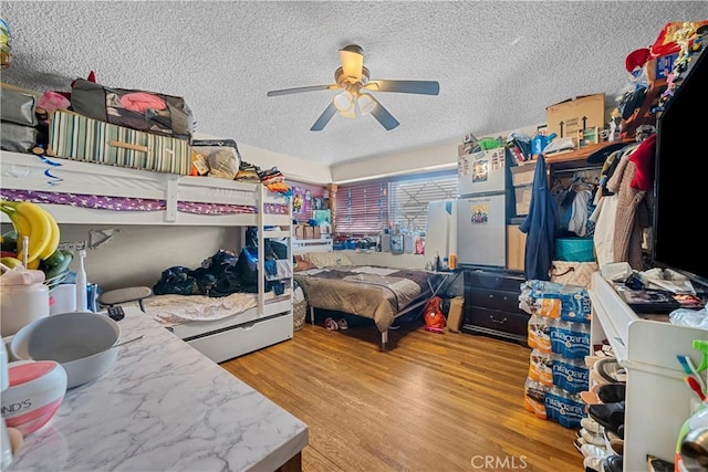 bedroom featuring ceiling fan, light hardwood / wood-style floors, and a textured ceiling