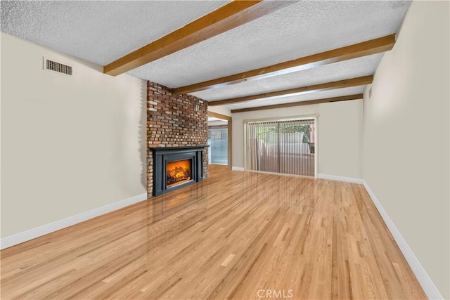 unfurnished living room featuring a fireplace, wood-type flooring, a textured ceiling, and beam ceiling