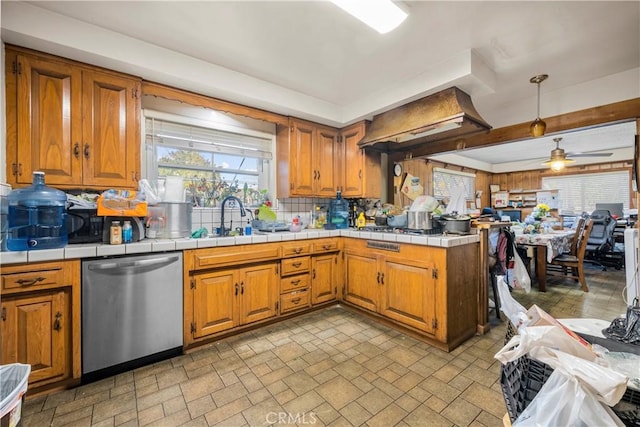 kitchen with ceiling fan, tile counters, sink, stainless steel dishwasher, and backsplash