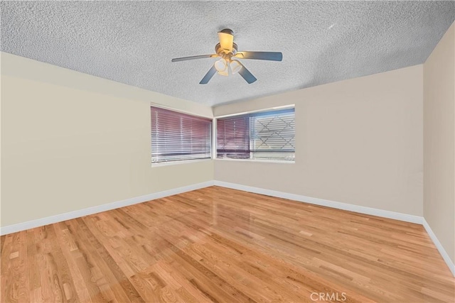 empty room with ceiling fan, wood-type flooring, and a textured ceiling