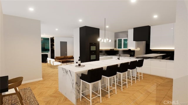 kitchen with a kitchen bar, a center island, pendant lighting, white cabinets, and light parquet flooring