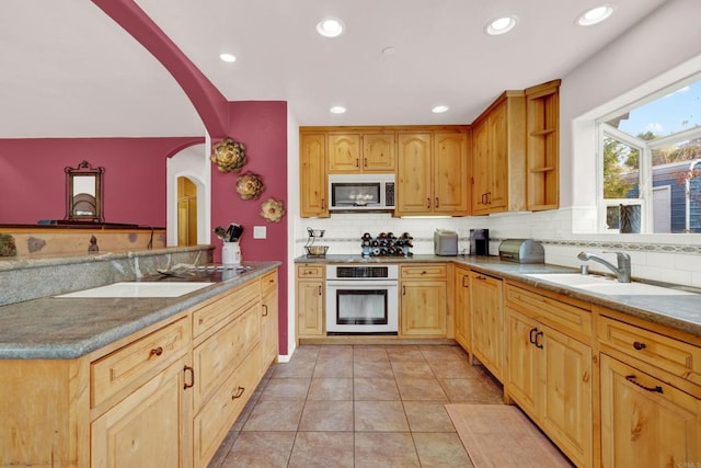 kitchen with kitchen peninsula, tasteful backsplash, white oven, sink, and light tile patterned floors