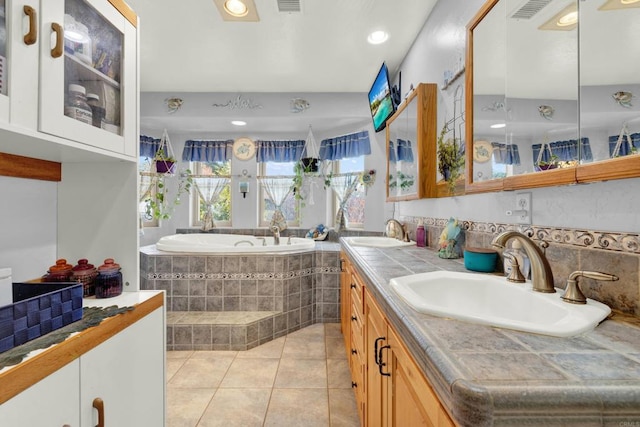 bathroom featuring vanity, a relaxing tiled tub, and tile patterned floors