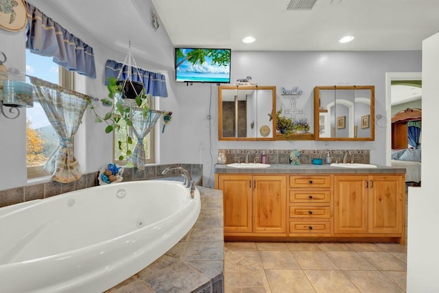 bathroom featuring tile patterned floors, vanity, and tiled bath