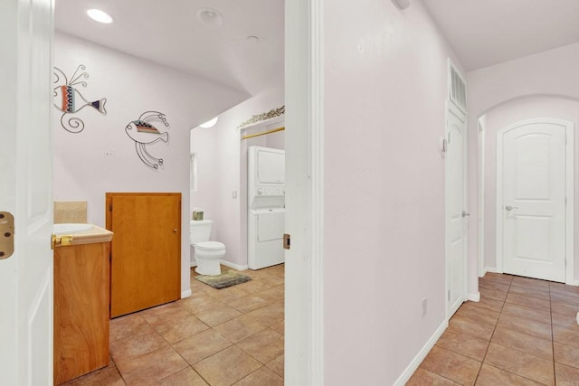 bathroom with tile patterned flooring, vanity, toilet, and stacked washer and dryer