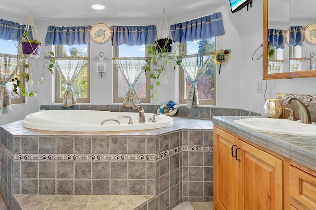 bathroom with vanity and tiled tub