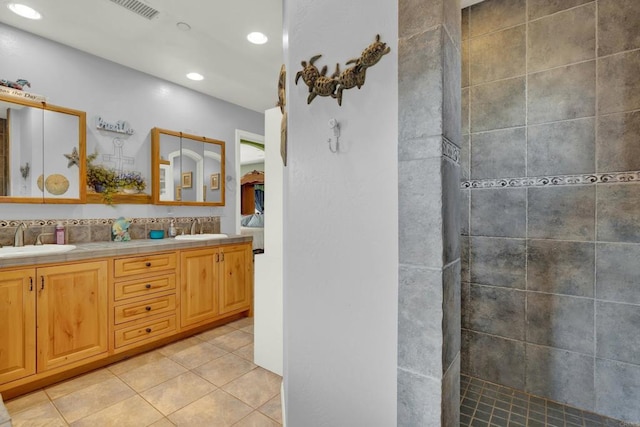 bathroom featuring tile patterned flooring, vanity, and tiled shower