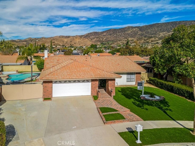 view of front of property with a mountain view, a garage, and a front lawn