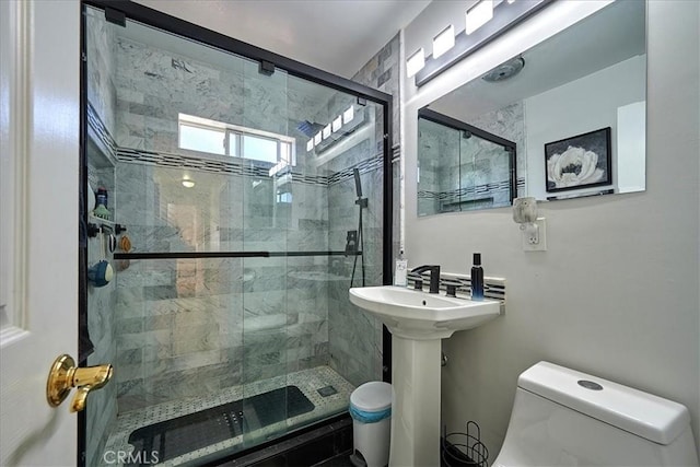 bathroom with a shower with shower door and toilet