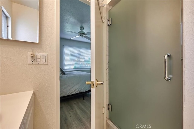 bathroom featuring a textured ceiling, ceiling fan, hardwood / wood-style floors, and an enclosed shower