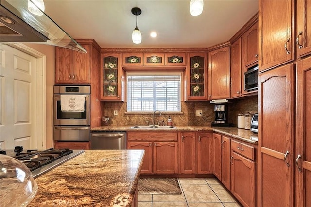 kitchen featuring hanging light fixtures, stone counters, sink, and appliances with stainless steel finishes