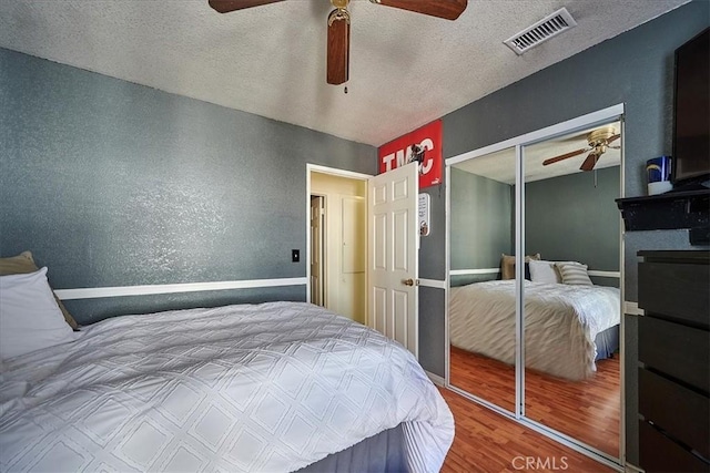 bedroom featuring hardwood / wood-style floors, a textured ceiling, a closet, and ceiling fan