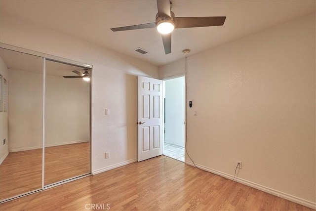 unfurnished bedroom with ceiling fan, a closet, and light wood-type flooring