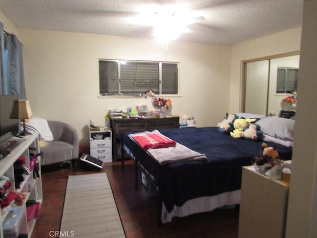 bedroom featuring a textured ceiling, a closet, ceiling fan, and dark wood-type flooring