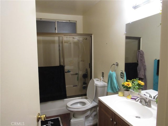 full bathroom featuring vanity, hardwood / wood-style flooring, toilet, and bath / shower combo with glass door