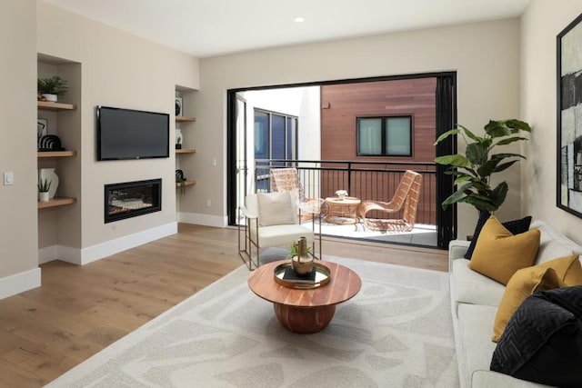 living room with built in shelves and light hardwood / wood-style flooring