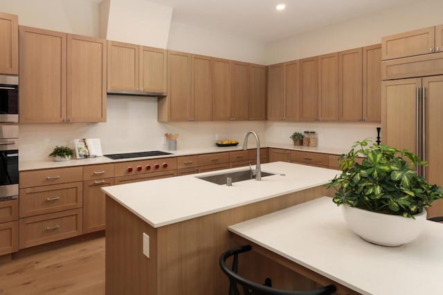 kitchen with a kitchen bar, wall oven, electric stovetop, light hardwood / wood-style flooring, and sink