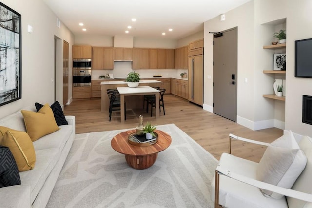 living room featuring light wood-type flooring and built in features