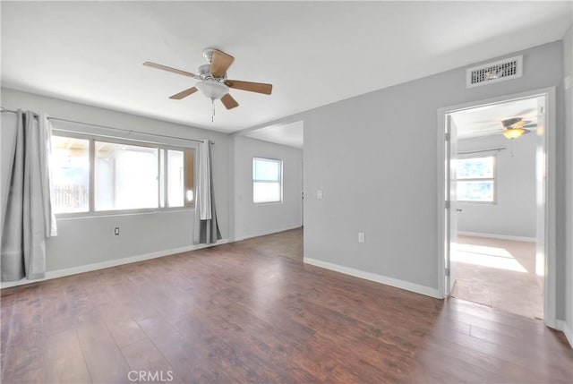 spare room featuring dark hardwood / wood-style floors, ceiling fan, and a healthy amount of sunlight