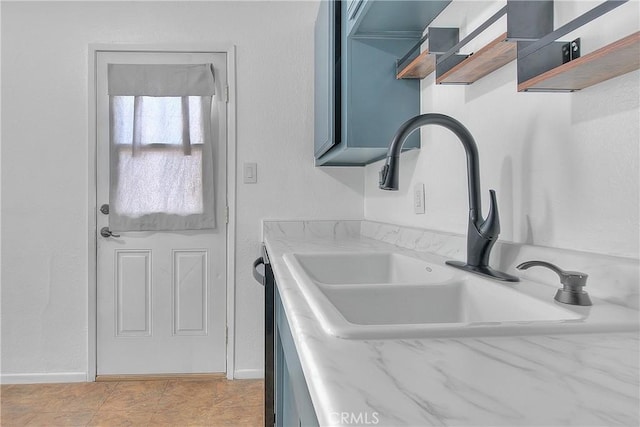 kitchen featuring light tile patterned floors, blue cabinets, and sink