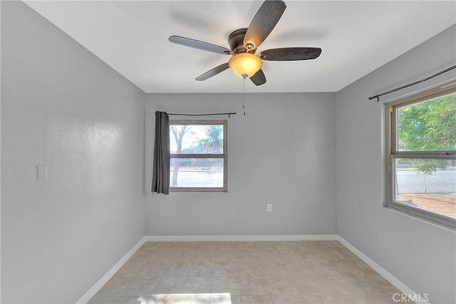 empty room with a wealth of natural light, ceiling fan, and light tile patterned flooring