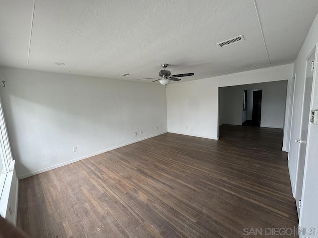 unfurnished room with a textured ceiling, dark hardwood / wood-style floors, and ceiling fan