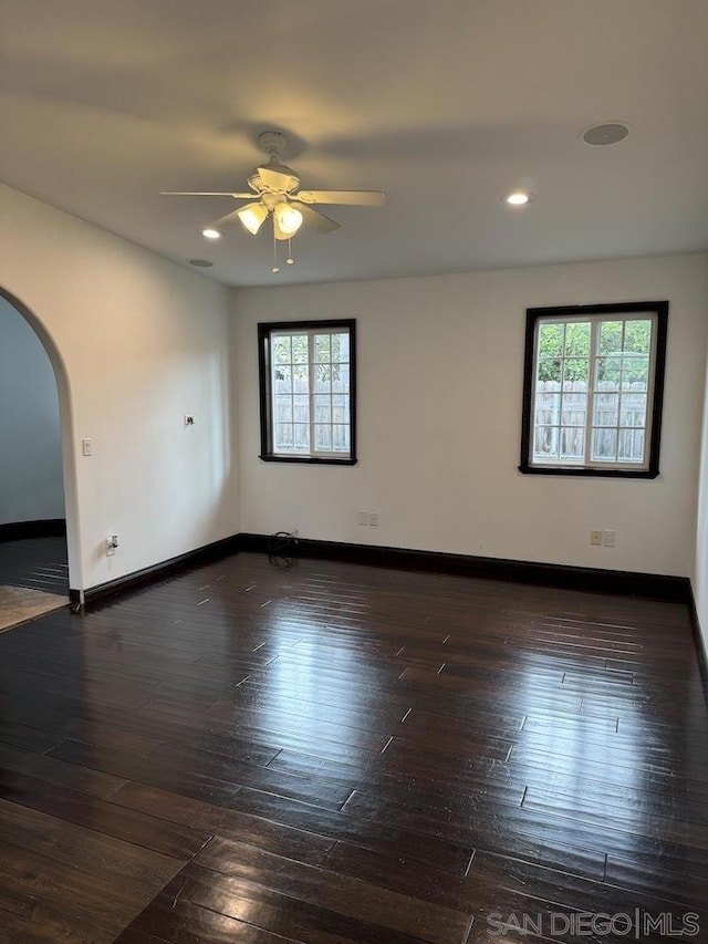 spare room with a wealth of natural light, ceiling fan, and dark hardwood / wood-style floors