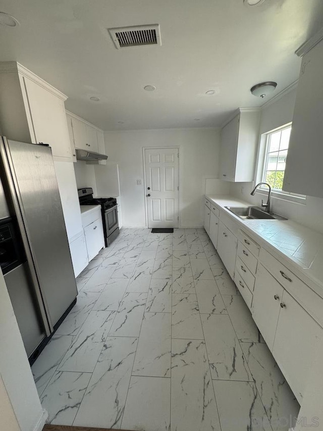 kitchen featuring ornamental molding, stainless steel appliances, sink, white cabinets, and tile counters