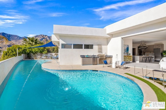 view of pool featuring a mountain view, exterior kitchen, and a patio