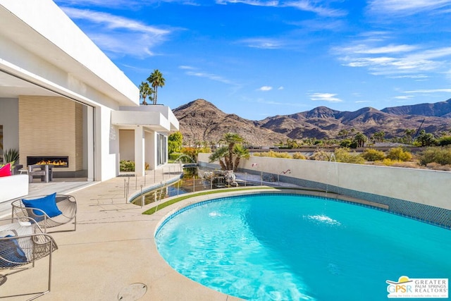 view of pool with pool water feature, a mountain view, and a patio area