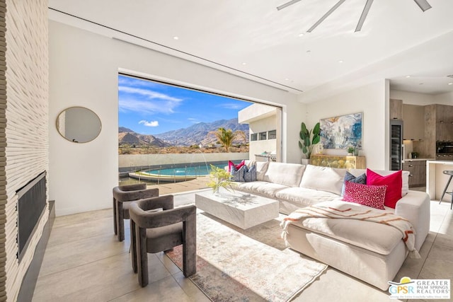 living room with a mountain view, a fireplace, and ceiling fan