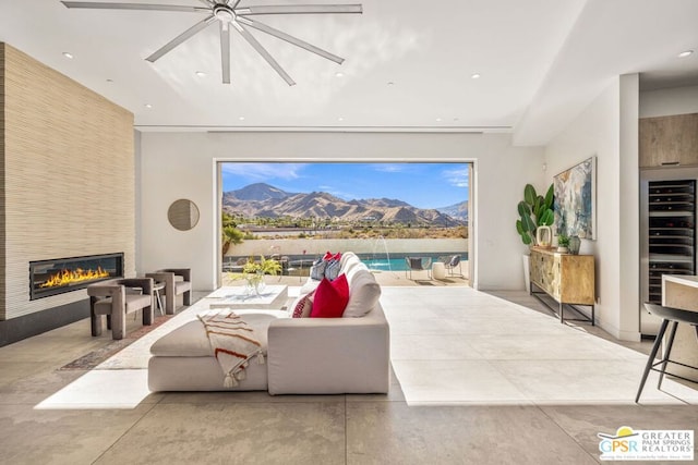 living room with ceiling fan, a mountain view, a large fireplace, and wine cooler