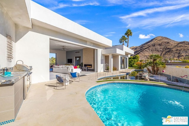 view of swimming pool featuring a mountain view, outdoor lounge area, a patio, and ceiling fan