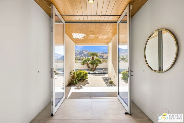 doorway to outside featuring wood ceiling, a wealth of natural light, a mountain view, and a wall of windows