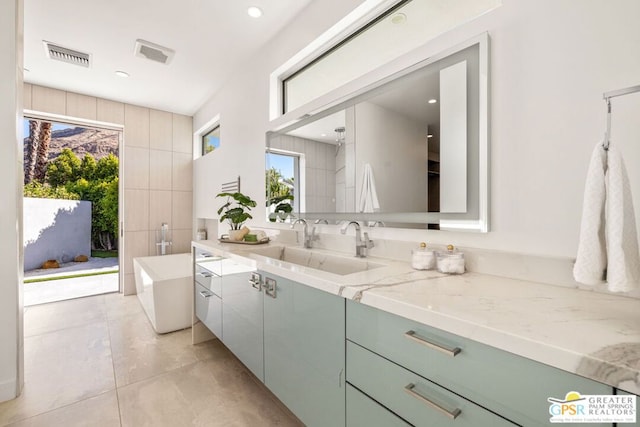 bathroom with tile patterned floors, vanity, and a tub to relax in