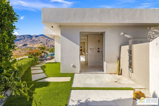 view of exterior entry with a patio area and a mountain view