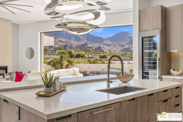 kitchen with a mountain view, a fireplace, sink, and beverage cooler