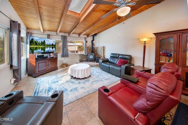 living room with a wood stove, vaulted ceiling with skylight, ceiling fan, light tile patterned flooring, and wood ceiling