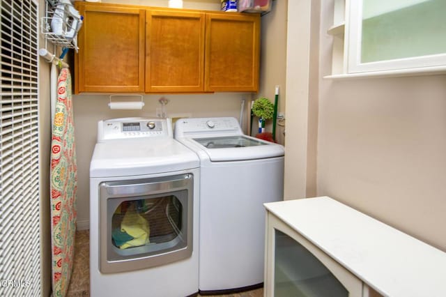 clothes washing area with washer and clothes dryer and cabinets