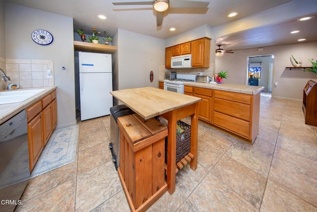 kitchen with tile counters, sink, a center island, tasteful backsplash, and white appliances