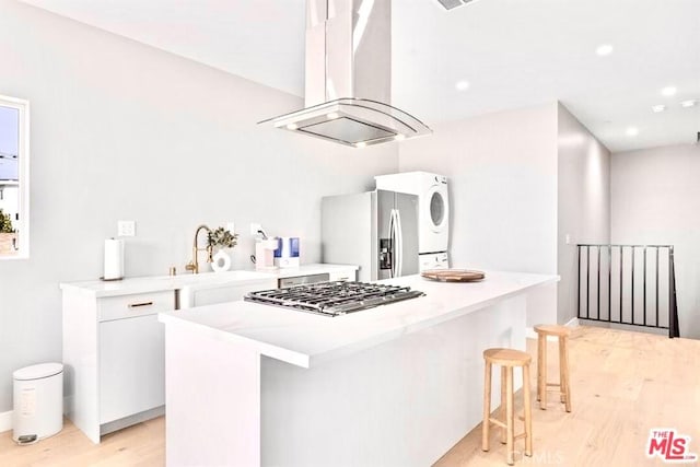 kitchen with a kitchen island, island exhaust hood, appliances with stainless steel finishes, white cabinets, and light wood-type flooring