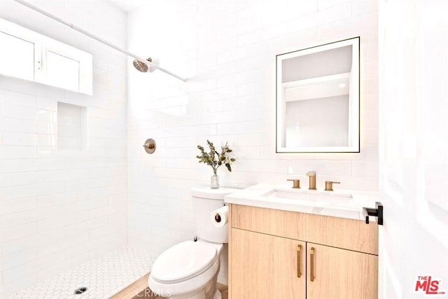 bathroom with a tile shower, vanity, and toilet