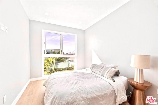 bedroom featuring lofted ceiling and light wood-type flooring